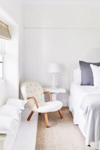 A mostly white summer bedroom with gray pillow