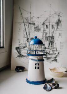 Miniature DIY lighthouse placed in front of the blueprint of a ship 