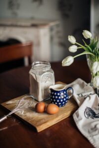 Flour jar, eggs, mug, and tea towel on a small table