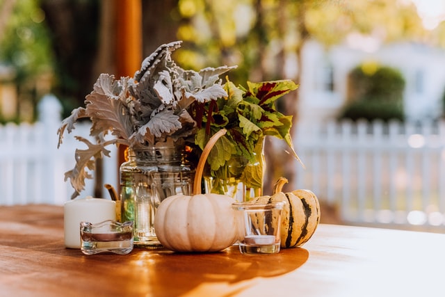 Pumpkins, glass, jar, and other budget fall decor items on a table