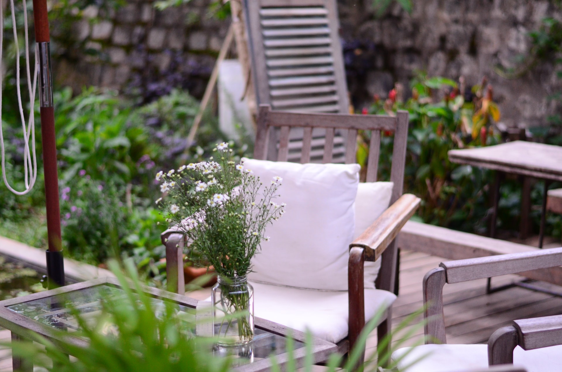 A table and chair in a patio having lots of greenery