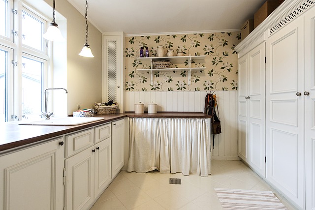 A kitchen cabinet covered with a curtain, and above that cabinet is wall that’s been decorated using a floral wallpaper
