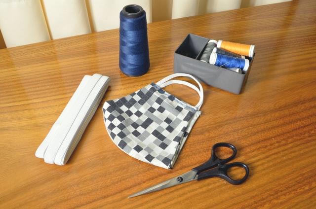 A table with DIY budget decorating project items, like black-handled scissors and blue threads